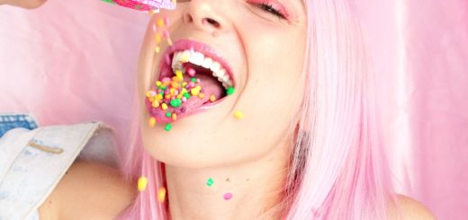 Woman With Pink Hair Pouring Nerds Candy in Her Mouth