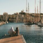 Couple and dog relaxing by the harbor with Marseille skyline.