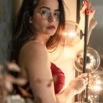 A woman in a red dress looking at herself in a mirror