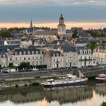 Historic cityscape of Angers, France, featuring charming architecture along the river at sunset.