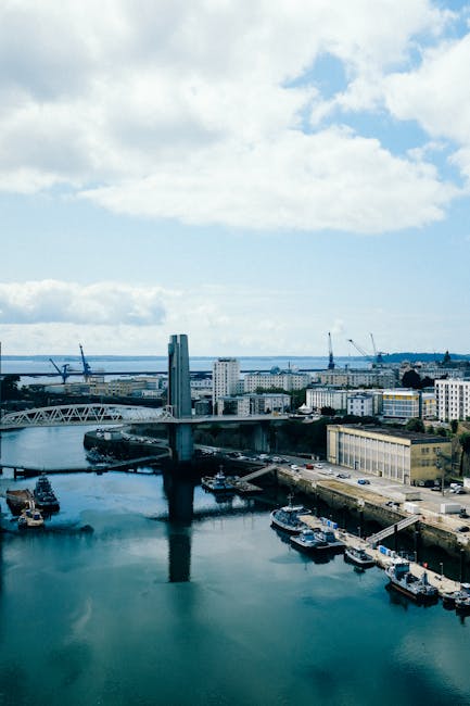 A vibrant urban cityscape with modern architecture and a bustling harbor under a cloudy sky.