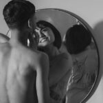 Une photographie romantique en noir et blanc d'un couple partageant un moment intime, refl&eacute;t&eacute; dans un miroir.