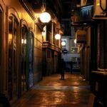 Une all&eacute;e urbaine sombre et &eacute;troite illumin&eacute;e par des lampadaires chauds la nuit, cr&eacute;ant une atmosph&egrave;re m&eacute;lancolique.