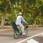 Un cycliste traverse un parc urbain verdoyant &agrave; Paris par une journ&eacute;e ensoleill&eacute;e.