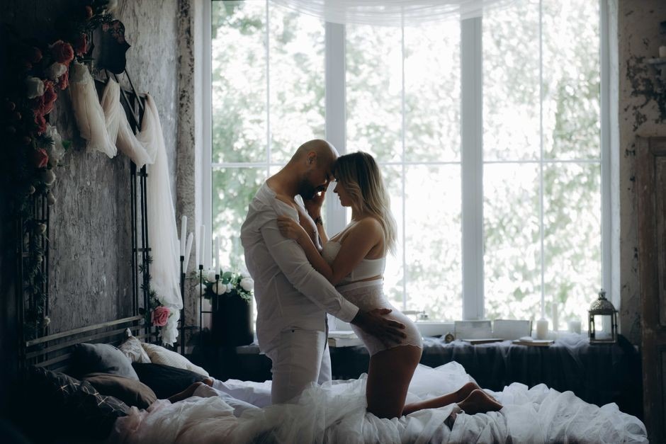 Un couple partage un moment intime dans une chambre chic et ensoleillée avec une décoration vintage.
